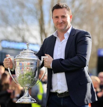 Photograph of Rob Smethurst, owner of Macclesfield FC holding a football trophy